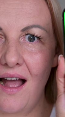 Cep telefonu reklamcılığı yapan bir kadın elinde akıllı telefon ve yeşil ekranlı içeriği izliyor. Yüksek kalite 4k görüntü