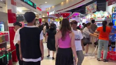 Erkek kız büyük iskelede yürüyüp kumar makineleriyle her yere bakıyor. Çocuklar, kadınlar ve erkekler izinli. Vietnam Ho Chi Minh Şehri 10.12.2024 'te bir yiyecek pazarı arıyorlar.