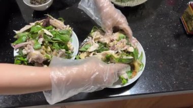 Vietnamlı tavuk, yılbaşı yemeklerinde tek kullanımlık eldiven pişiren marul yapraklı kesilmiş tavuğu tabağa koydu. Yüksek kalite 4k görüntü