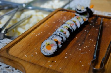 Sushi dürümleri yakın plan suşi için yemek çubuklarıyla alınır. Bir restoranda Japon mutfağı suşisi. Somon ve sebzeli suşi. Japon restoran menüsü. Yan görüş. Yüksek kalite 4k görüntü