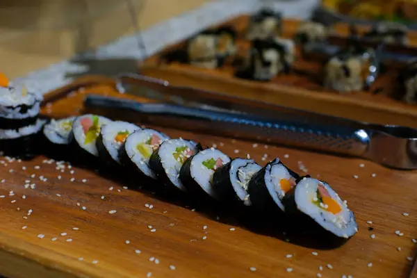 Sushi dürümleri yakın plan suşi için yemek çubuklarıyla alınır. Bir restoranda Japon mutfağı suşisi. Somon ve sebzeli suşi. Japon restoran menüsü. Yan görüş. Yüksek kalite 4k görüntü