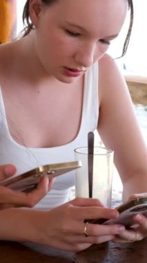 Ellerinde telefon olan iki kız birbirleriyle bağlantı kurarak maske takan Avrupalı turist Asyalı kadınların kafede kahve almalarını sağlıyorlar. Faturayı telefonla ödeyen masada oturuyor..