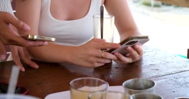 Ellerinde telefon olan iki kız birbirleriyle bağlantı kurarak maske takan Avrupalı turist Asyalı kadınların kafede kahve almalarını sağlıyorlar. Faturayı telefonla ödeyen masada oturuyor..