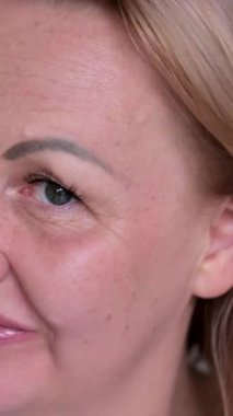 Sarışın bir kadının, altın dalgalı saçlarını tararken, elleri gri bir arka planda olan telleri ayırırken çekilmiş görüntüsü. Renklerin sonucu, renklendirme, perma. Kapatın. Kadın saçını tarıyor.