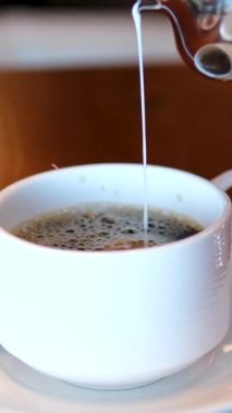 Siyah çay çayına süt ekle. Beyaz ve kahverengi kıvrımlı. - Yakın çekim. Ağır çekim. Döndürme. Soyut kaotik hareket