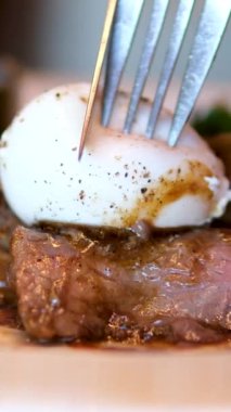 Bir parça ekmeğin üzerinde haşlanmış yumurta ve yeşil marul yaprakları tabakta döner, yakın plan, kahvaltı konsepti. rafadan yumurta. Yumurta sarısı protein ızgarasından, biftek ve yumurta karışımından akar.