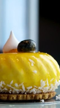 Lezzetli, fırınlanmış, çok katmanlı mangolu, çarkıfelek meyveli peynirli kek dilimi beyaz tabakta jöle jöleli ve yakın çekte bir kaşıkla yemek. mango keki