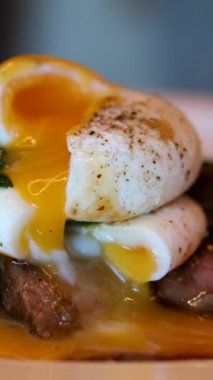 Bir parça ekmeğin üzerinde haşlanmış yumurta ve yeşil marul yaprakları tabakta döner, yakın plan, kahvaltı konsepti. rafadan yumurta. Yumurta sarısı protein ızgarasından, biftek ve yumurta karışımından akar.