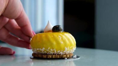 Lezzetli, fırınlanmış, çok katmanlı mangolu, çarkıfelek meyveli peynirli kek dilimi beyaz tabakta jöle jöleli ve yakın çekte bir kaşıkla yemek. mango keki