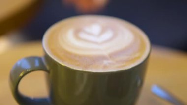 Latte sanatıyla kahve bardağının en üst görüntüsü. Kalp şeklinde sıcak Latte sanat kahvesi. Sıcak kahveyle dolu bir fincanda beyaz kalp şeklinde latte sanat eseri. Yüksek kalite 4k görüntü