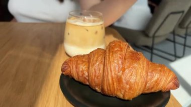 Güzel bir kafede kapuçino servisi yapan buzlu latte bayan. Bir kafede taze çiçeklerle vurulmuş ve kahve servisi yapan ve kruvasan yiyen bir kadın. Sessiz bir kafede lezzetli bir kahvaltı..