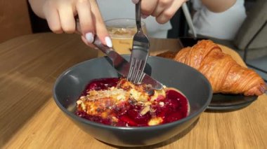 Reçelli peynirli kek. Çatal bir parça süzme peynirli krep kırar. Rus ve Ukrayna yemekleri. Bıçak ve çatalla yenecek süzme peynirli krep.