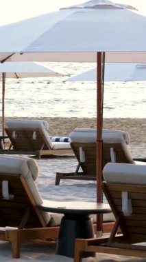 Güzel sahil. Deniz kenarındaki sahilde sandalyeler. Yaz tatili ve turizm için tatil konsepti. İlham verici tropikal bir manzara. Sahilde şemsiyeli güneşlikler.