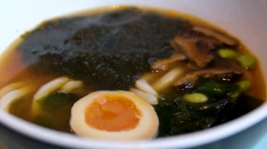Yumurta sarısı erişteleri toplarken paslanmaz çubuklar haşlanmış domuz eti ve topun üzerine baharatlı Tom yum çorbası dökülüyor. Yumurtalı Tom Yum çorbası