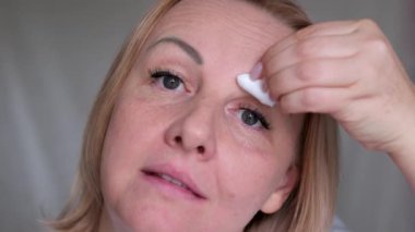 Kız, makyajı pamuk pedle temizler ve suyu yüzünden ve gözlerinden çıkarır. Makyajı pamukla sil