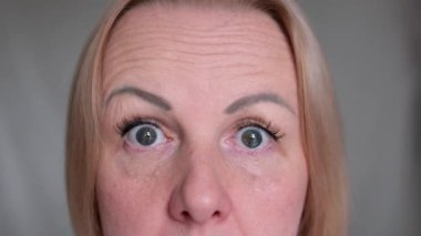 Genç bir kadının aşırı yakın çekimi gözlerini açar ve kameraya bakar ve geniş bir bakış açısıyla şaşırmış bir ifade oluşturur. Şaşırmış bir kadının gözleri
