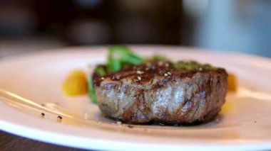 Bifteği mikro yeşil ve siyah arka planda ağır çekimde dönen tuzla kapat. İki parça fileminyon. Filet Mignon