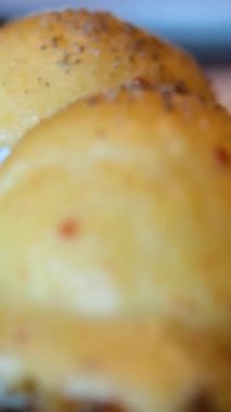 Sıvı yumurta sarısı tükenen iki yumurtalı Benedict. İki haşlanmış yumurta patates krepi ya da domatesli kızarmış ekmek, kızarmış soğan ve Hollandez soslu pastırma..
