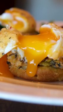 Sıvı yumurta sarısı ikiye bölünmüş ve yumurta sarısı sandviç ve tabakta aşağı akıyor. Lezzetli bir kahvaltı menüsünü yakından çek. Kahvaltıda Bali Kafe 'de nefis yemekler servis ediliyor..