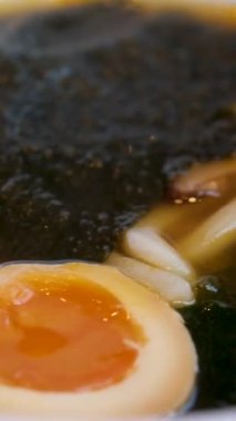 Yumurta sarısı erişteleri toplarken paslanmaz çubuklar haşlanmış domuz eti ve topun üzerine baharatlı Tom yum çorbası dökülüyor. Yumurtalı Tom Yum çorbası