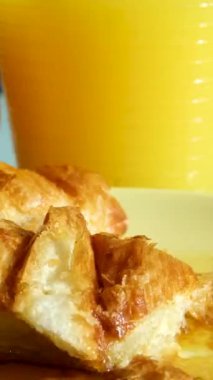 Akçaağaç şuruplu kruvasan, portakal suyu ve portakal suyunun arka planında bıçak ve çatalla taze pişmiş kruvasan kesiyor. Pencereden güneş ışığı