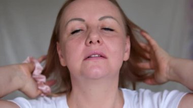 Saçını toka ile düzelten kadın at kuyruğunu düzelten güzel, yetişkin kadın saçlarını diken kadın. Yüksek kalite 4k görüntü