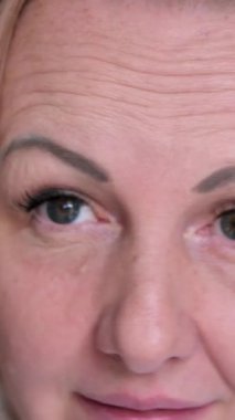 Orta yaşlı sarışın bir kadın banyo aynasının önünde saçını tarıyor. Saçın sağlıklı uzayan uçlarına bakar ve mutlulukla gülümser. Yüksek kalite 4k görüntü