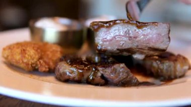 Mutfak bıçağı ve barbekü çatalı kullanarak biftek dilimine aşırı yakın çekim. Mükemmel pişirilmiş et dilimleme, yavaş çekim. Orta pişmiş biftek.