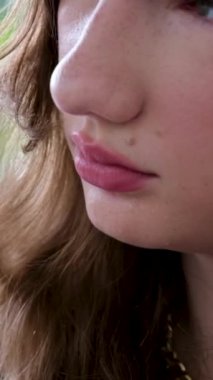 Kırmızı çizgileri, pembe dudakları, makyajı, kirpikleri, üzgün çilleri olan genç bir kızın yakın çekimi. Yüksek kaliteli FullHD görüntüler