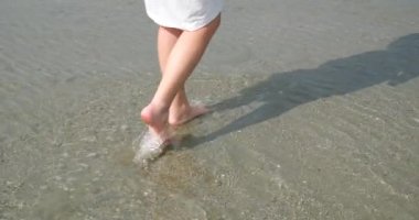 Arka kadın sahilde yalınayak yürür ve deniz boyunca yürür. Gün batımında deniz suyu köpüğü kumu ve bronzlaşmış genç bir kızın ayaklarını yıkar. Hafta sonu doğa gezisi..