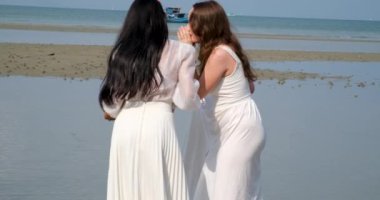 Kız Küçük Sır 'ı Söylüyor, Kahkaha. Beyaz Asyalı-Avrupalı şakası yapan iki kız kulağına fısıldıyor nehirde su kenarında durduğunu fısıldıyor