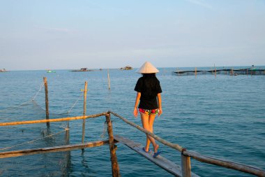 Vietnam Phu Quoc Adası 'ndaki tropikal sahil iskelesinde duran lüks villaların önünde duran genç ve güzel bir kadın. Yüksek kalite fotoğraf