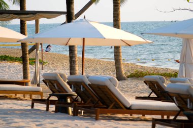 Kenarda iki plaj sandalyesi ve bir plaj şemsiyesi bulunmaktadır. Yaz tatili ile ilgili fotoğraflar. Dikey pozisyonda vurulmuş. Yüksek kalite fotoğraf