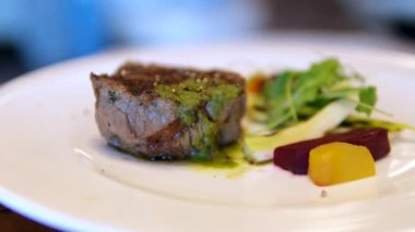 Lezzetli fileto biftek, hamursuz soslu, mikro yeşil salata ve süslü bir restoranda vişneli domates, öğle yemeği, 4K shot. Yüksek kalite 4k görüntü