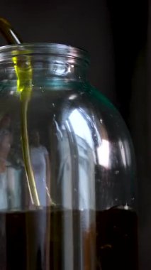Bir şişe zeytinyağı yavaş çekimde Macro shot 'tan aşağı dökülüyor. Yüksek kalite 4k görüntü