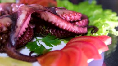 Sebzelerle servis edilen ahtapot, deniz ürünleri. Kaynamış ahtapot dokunaçları koyu taş bir tabakta, Asya, Akdeniz mutfağı, akşam yemeği. Üst Manzara. Siyah arka planda restoran menüsü. 4k 