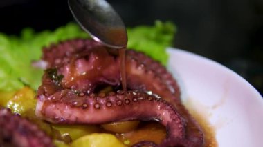 Sebzelerle servis edilen ahtapot, deniz ürünleri. Kaynamış ahtapot dokunaçları koyu taş bir tabakta, Asya, Akdeniz mutfağı, akşam yemeği. Üst Manzara. Siyah arka planda restoran menüsü. 4k 