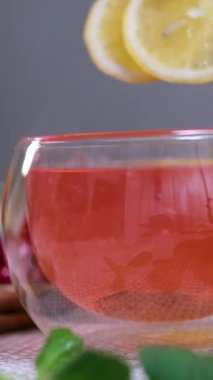 Portakallı, limonlu ve limonlu çayı şeffaf çaydanlıktan bardağa doldurmak. Arka planda bal ve krep ile çay demlemek. Yavaş çekim çayı. Kırmızı amberli iki dilim limon.