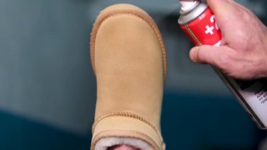 Sonbahar ve kıştan önce siyah süet botları hazırlıyor. Elinde çizme tutarken koruyucu ve besleyici süet bir krem sürüyor. Kış ayakkabı bakımı konusu. Tema bakımı. bej ugg çizmeleri