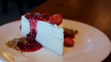 Beyaz pasta, ince pastalar, üzerinde çilek reçeli olan katmanlar kahvaltıda krema sürülmüş beyaz tabaktan ince bir kaşıkla yemek. Yüksek kalite 4k görüntü