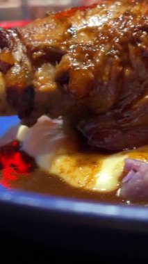 Etin üzerine kaşık sosu dök. Pişmiş kuzu budu. Kuzu etine koyu kırmızı sos ve salata. Şarabı ve yemek programı olan şefler masası. . 