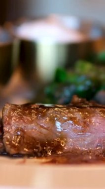 Siyah arka planda dönen bir çatalda taze ızgara biftek eti parçaları. Yiyeceğe yakın çekim. Orta pişmiş biftek.