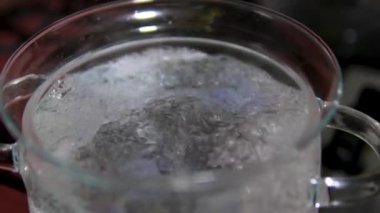 Buhar ve sıcak su kabarcıkları siyah zemin üzerinde kaynayan sıcak sudan yükseliyor. Ağır çekimde sıcak su kaynıyor. Yüksek kalite 4k görüntü