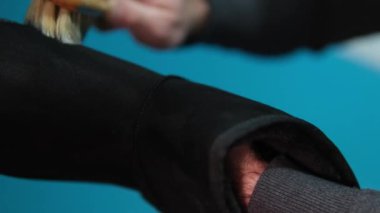 Stüdyoda siyah botları fırçayla temizleyen adam. Erkek, fırçayla nubuck ayakkabısı fırçalıyor. Kış ayakkabıları için bakım teması. Kirli kara sonbahar paçalarını yıkar, atölye ayakkabılarını temizler..