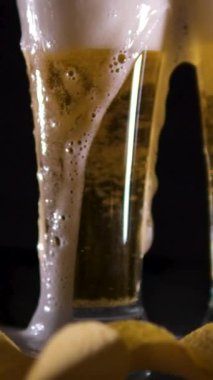 cips bira. Siyah arka plandaki masada bir bardak soğuk bira, patates cipsi tahta masaya düşüyor, altın bira doğal köpük, doğal alkollü soğuk içecek.. 