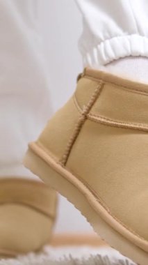 Ayaklarını Yatak Odasında Uyandırmak. Rahat ve rahat bir sabah. Sabah erken yatma vakti. Kadın terlikler halıda, kanepenin yanında. Halıda uyandıktan sonra kadın bacakları. Uyanın Yumuşak peluş bej ugg çizmeleri giyin