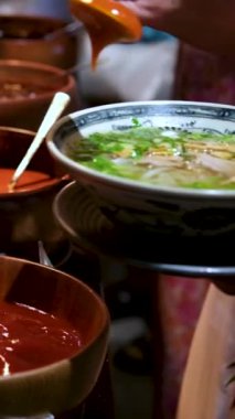 Kore peynirli toppoki ve Çin yağlı kuru erişteleri kızarmış tavukla servis ediliyor. Salata üzerine açık büfe sosu.