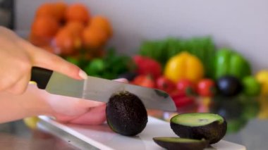 Mutfakta kesme tahtasının üzerinde avokado kesen şefin ellerini kapat.