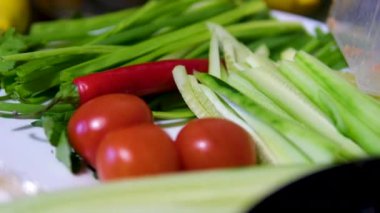 Kesme tahtasının üzerinde bir mutfak bıçağıyla sebzeleri kes. Mutfak masasına bir tabak sebze koy. Domates salatalıklı lahana soğanlı salata biberi. Yüksek kalite 4k görüntü