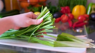Ev yapımı yemek hazırlığı için taze soğan doğrayan ellere yakın çekim. yeşil soğan kesme tahtası